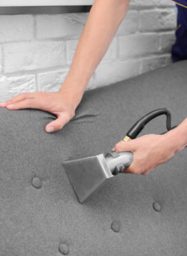 Dry cleaning worker removing dirt from sofa indoors