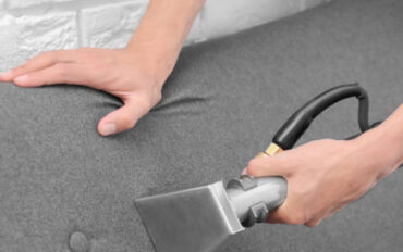 Dry cleaning worker removing dirt from sofa indoors